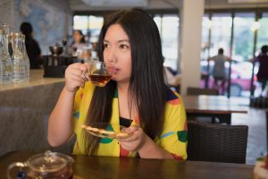 Woman in colorful dress is drinking and sipping hot tea